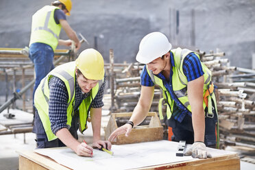 Bauarbeiter und Ingenieur bei der Überarbeitung von Bauplänen auf der Baustelle - CAIF11641