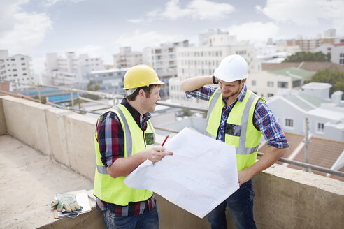 Bauarbeiter und Ingenieur bei der Überprüfung von Bauplänen auf einer Hochhausbaustelle - CAIF11646
