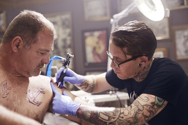 Tattoo artist tattooing man’s shoulder - CAIF11661