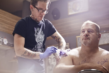 Tattoo artist tattooing man’s shoulder - CAIF11664