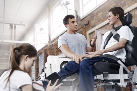 Physiotherapeut erklärt dem Mann die Geräte, lizenzfreies Stockfoto