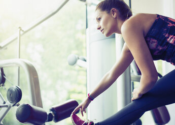 Konzentrierte Frau streckt ihr Bein im Fitnessstudio - CAIF11698