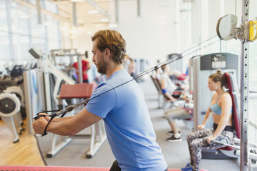 Mann benutzt Kabelübungsgerät im Fitnessstudio - CAIF11707