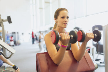 Frau macht Bizeps-Curls mit Kurzhanteln im Fitnessstudio - CAIF11710