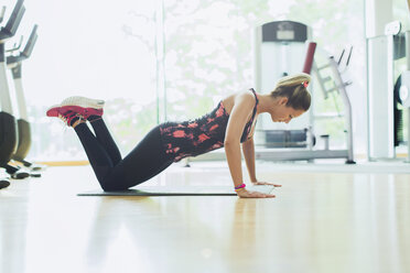 Frau macht Liegestütze auf den Knien im Fitnessstudio - CAIF11737