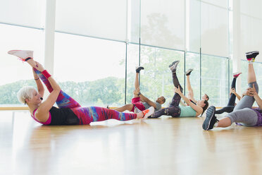 Fitnesslehrer, der einen Sportkurs leitet und die Beine streckt - CAIF11740