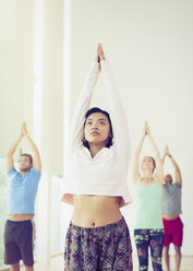Ernste Frau mit erhobenen Armen im Yoga-Kurs - CAIF11766