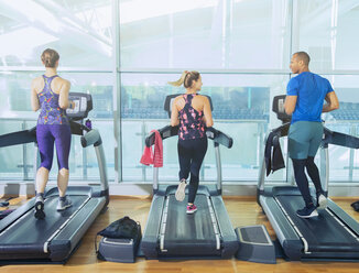 Mann und Frauen laufen auf Laufbändern im Fitnessstudio - CAIF11809