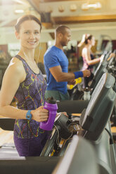 Portrait lächelnde Frau mit Wasserflasche auf dem Laufband im Fitnessstudio - CAIF11821