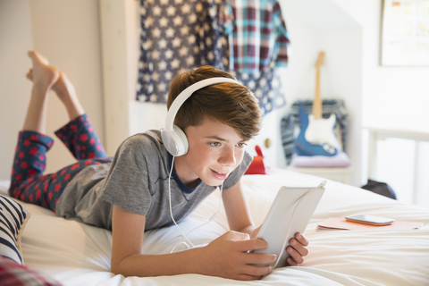 Junge mit Kopfhörern, der Musik auf einem digitalen Tablet hört, lizenzfreies Stockfoto