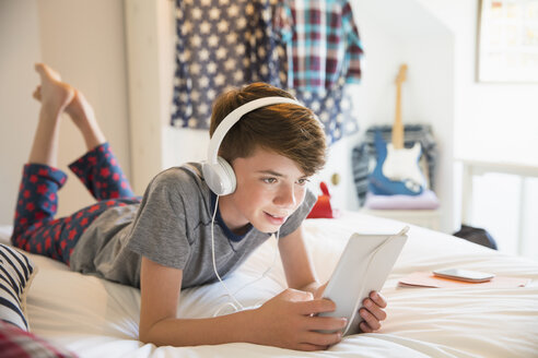 Junge mit Kopfhörern, der Musik auf einem digitalen Tablet hört - CAIF11840