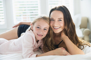 Portrait lächelnde Mutter und Tochter auf dem Bett liegend - CAIF11846