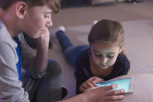 Bruder und Schwester spielen ein Spiel auf einem digitalen Tablet - CAIF11849