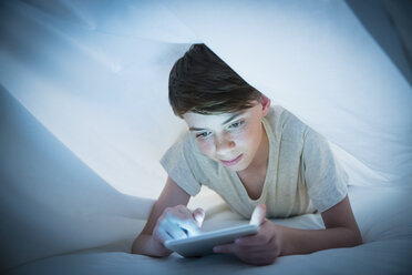 Junge benutzt digitales Tablet unter Laken - CAIF11851