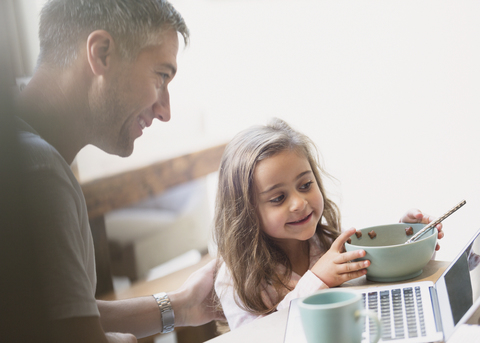 Vater und Tochter beim Frühstück am Laptop, lizenzfreies Stockfoto