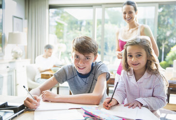 Portrait smiling brother and sister doing homework - CAIF11856