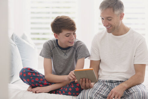Vater und Sohn im Pyjama mit digitalem Tablet - CAIF11861