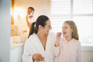 Mother and daughter brushing teeth in bathroom - CAIF11865