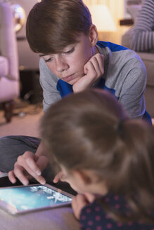 Bruder und Schwester spielen ein Videospiel auf einem digitalen Tablet - CAIF11866