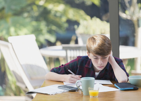 Junge macht Mathe-Hausaufgaben am Esstisch - CAIF11871