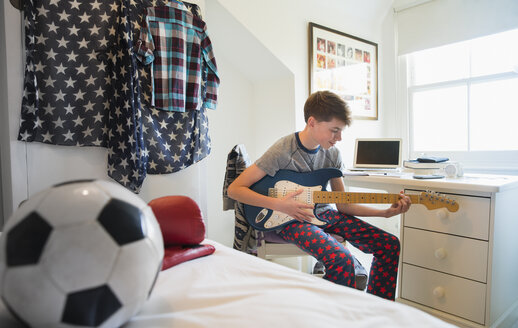 Junge spielt E-Gitarre im Schlafzimmer - CAIF11876