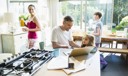 Familie mit Frühstück und Laptop in der Morgenküche - CAIF11883