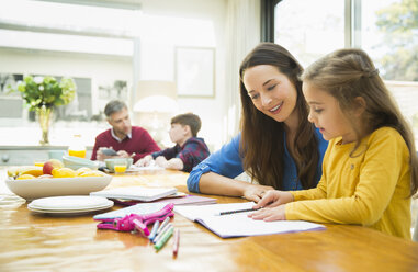 Mother and daughter doing homework at dining table - CAIF11888