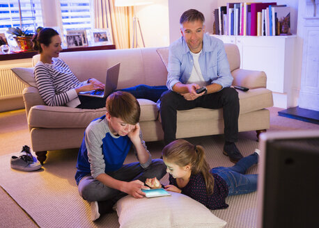 Familie entspannt sich mit Technik im Wohnzimmer - CAIF11892