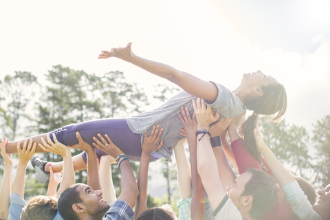 Unbekümmerte Frau beim Crowdsurfen mit Unterstützung eines Teams, lizenzfreies Stockfoto