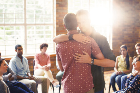 Männer umarmen sich in einer Gruppentherapie-Sitzung - CAIF11934