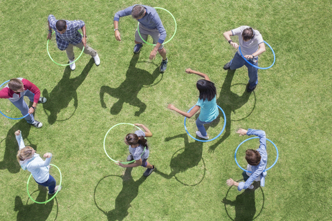 Menschen, die sich in Plastikreifen im sonnigen Gras drehen, lizenzfreies Stockfoto