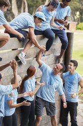 Teamkollegen helfen sich gegenseitig über die Mauer im Bootcamp-Hindernisparcours - CAIF11937