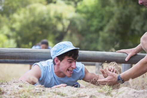 Teamkollege hilft Mann beim Kriechen im Bootcamp-Hindernisparcours - CAIF11941