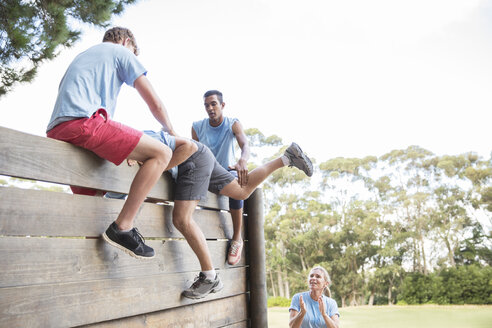 Mannschaftskameraden helfen Mann über die Mauer im Bootcamp-Hindernislauf - CAIF11953