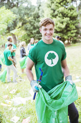 Porträt eines lächelnden Umweltschützers, der freiwillig Müll aufsammelt - CAIF11992