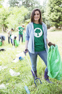 Porträt eines lächelnden Umweltschützers, der freiwillig Müll aufsammelt - CAIF11993