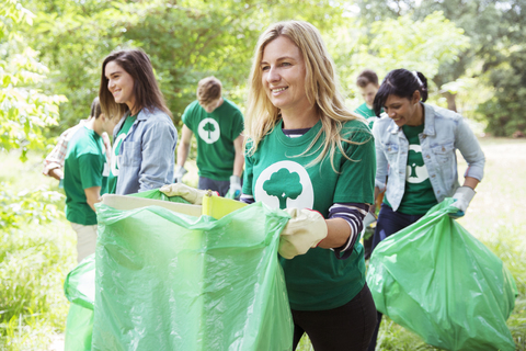 Lächelnder Umweltschützer sammelt freiwillig Müll auf, lizenzfreies Stockfoto
