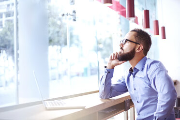 Pensive businessman at laptop in cafe - CAIF12040