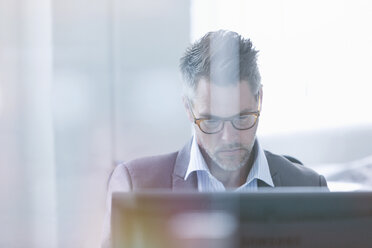 Focused businessman using computer in office - CAIF12086