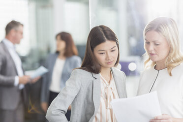 Businesswomen discussing paperwork in office - CAIF12087