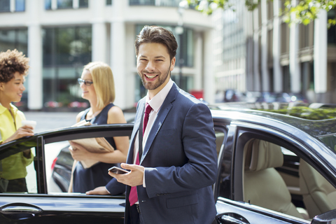 Geschäftsmann lächelnd vor Auto, lizenzfreies Stockfoto