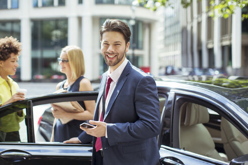 Geschäftsmann lächelnd vor Auto - CAIF12098