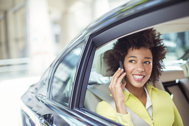 Geschäftsfrau, die auf dem Rücksitz eines Autos mit einem Handy telefoniert - CAIF12100