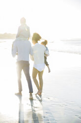 Family walking on beach in sunlight - CAIF12133