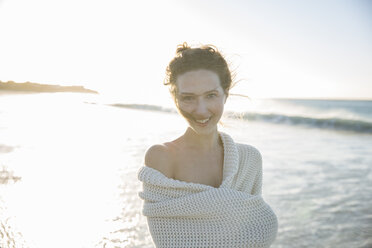 Portrait of young woman wrapped in blanket on beach - CAIF12135