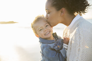 Mother kissing daughter on beach - CAIF12152