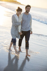 Junges Paar spaziert am Strand in der Abendsonne - CAIF12159