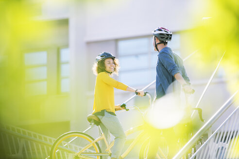 Mann und Frau mit Helmen auf Fahrrädern im Gespräch - CAIF12166
