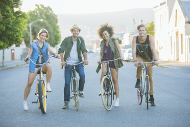 Porträt lächelnd Freunde sitzen auf Fahrrädern auf der Straße - CAIF12170