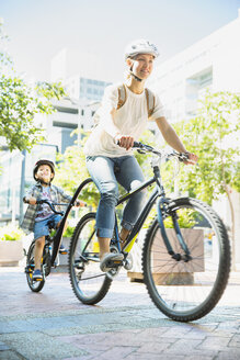 Mutter und Sohn fahren mit dem Fahrrad auf einem städtischen Weg - CAIF12173